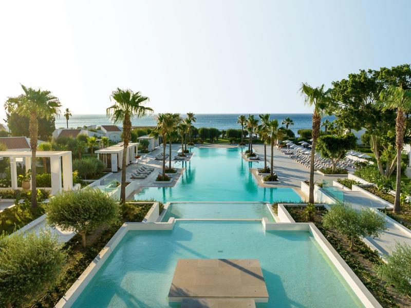 Area piscina di lusso con palme e vista mare in un resort alberghiero