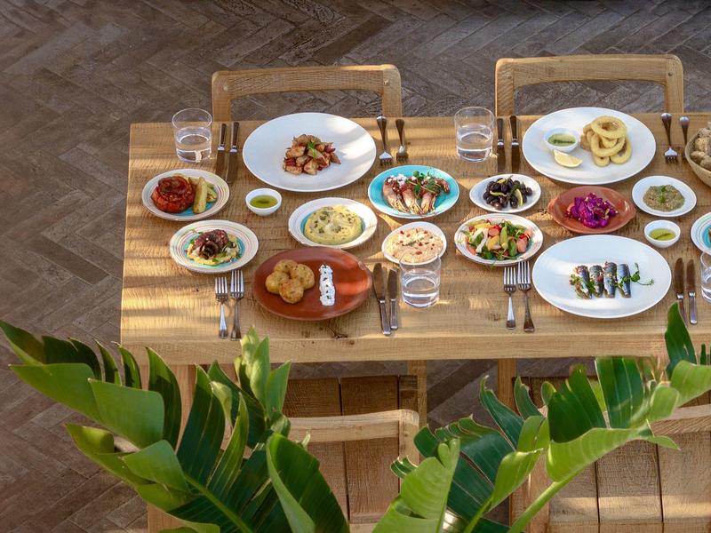 Un tavolo di legno apparecchiato con varie ciotole e piatti pieni di piatti colorati e bevande.