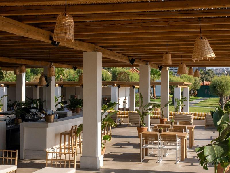 Area coperta di un hotel con travi di legno, tavoli e sedie all'aperto.
