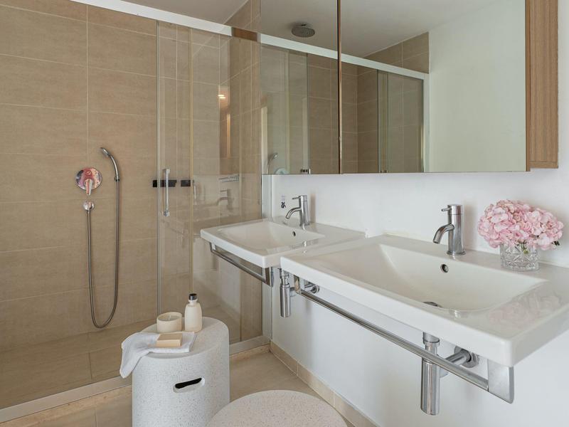 Bagno moderno con lavabo doppio e cabina doccia beige con parete in vetro