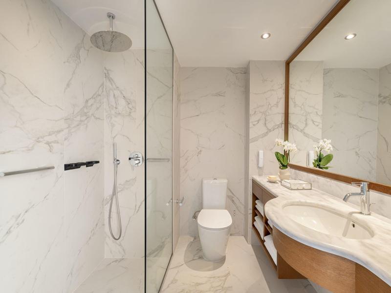 Bagno moderno con doccia, WC, doppio lavabo e grande specchio in stile marmo.