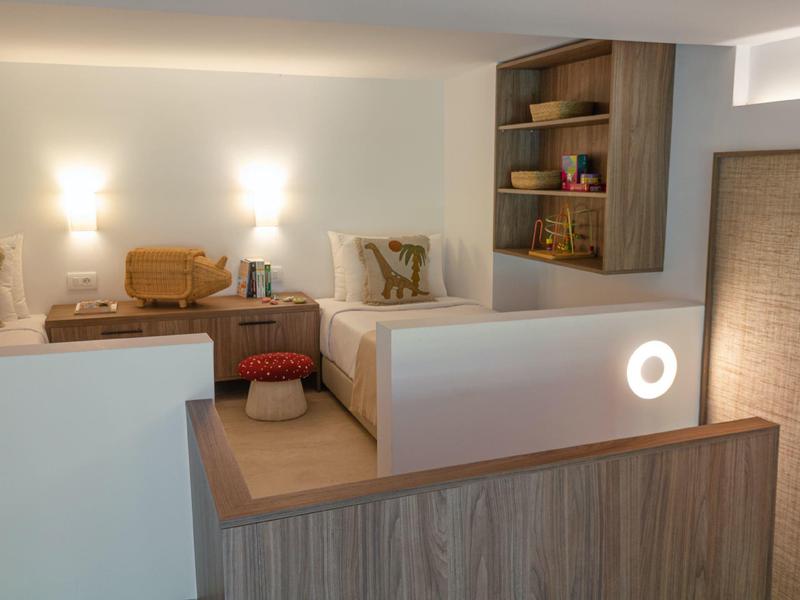 Camera d'albergo moderna con due letti, mobili in legno e un accento luminoso sulla parete.