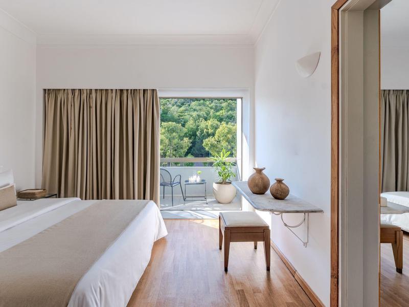 Camera luminosa con accesso al balcone e vista sul paesaggio verde.