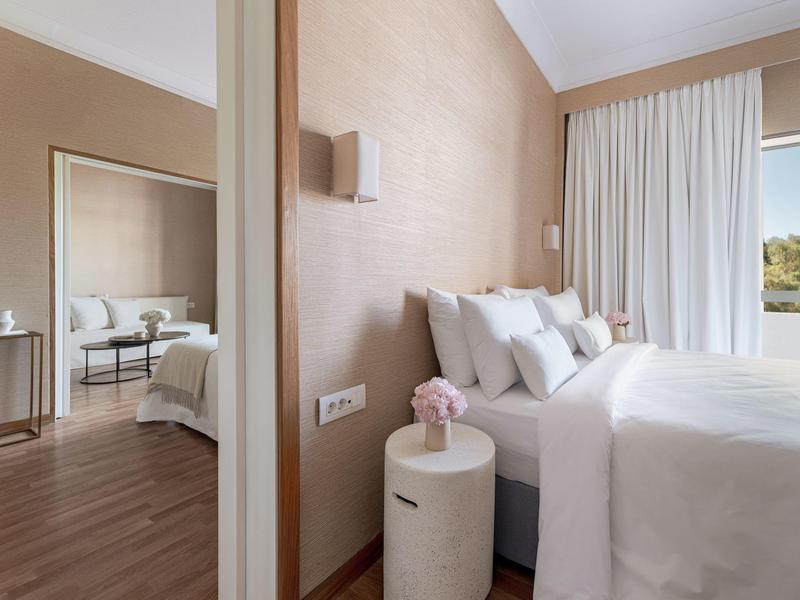 Camera da letto moderna con letto grande, tende bianche e zona salotto con divano.