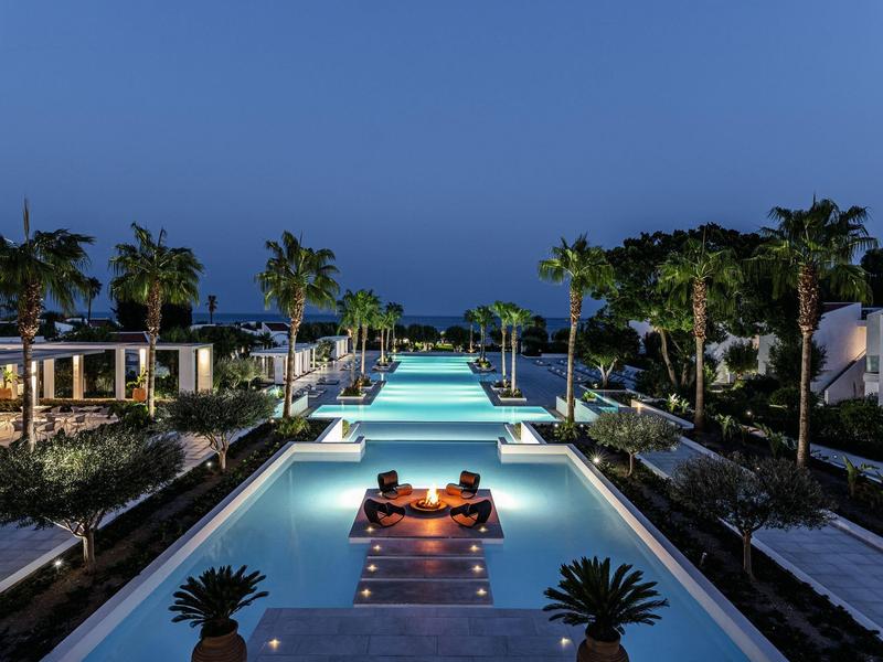 Area piscina di lusso con ospiti rilassanti e vista sul mare al crepuscolo