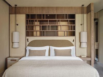 Chambre d'hôtel moderne avec lit double, étagères en bois et éclairage minimaliste.