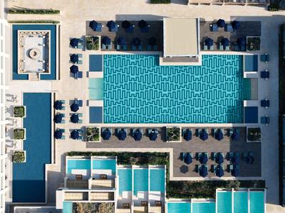 Vue aérienne d'une piscine d'hôtel moderne avec des transats et des parasols.