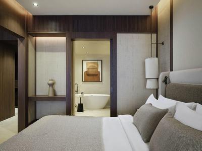 Chambre d'hôtel moderne avec lit confortable et vue sur salle de bain avec baignoire.