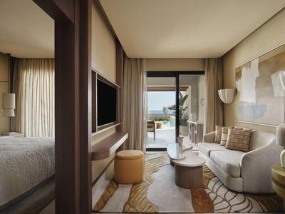Chambre d'hôtel moderne avec coin salon et vue sur la terrasse et la mer.