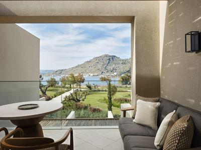 Balcon moderne avec coin salon donnant sur un jardin, la mer et des collines en arrière-plan.