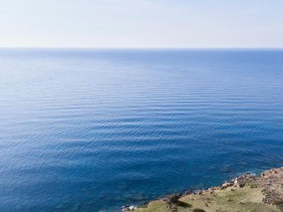Littoral avec mer bleue claire et rivage rocheux sous un ciel bleu.