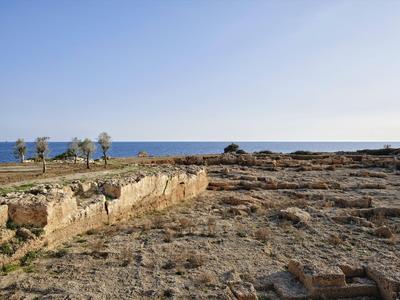 Paysage côtier aride avec des rochers et la mer sous un ciel clair.