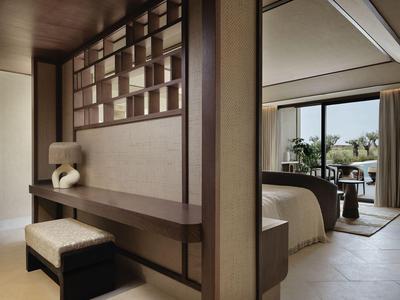 Chambre d'hôtel moderne avec lit, banc, bureau et grande fenêtre donnant sur l'extérieur.