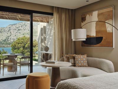 Salon d'hôtel confortable avec canapé, table ronde et vue sur la terrasse et la mer