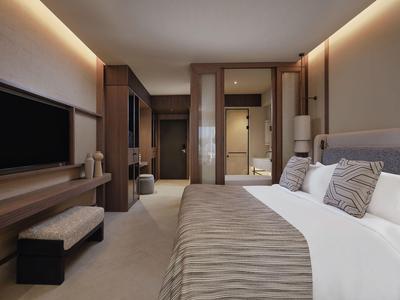 Chambre moderne avec lit, télévision et éclairage doux dans des tons neutres.