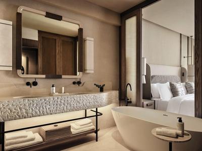 Salle de bains moderne avec baignoire indépendante, grand lavabo et vue sur la chambre.