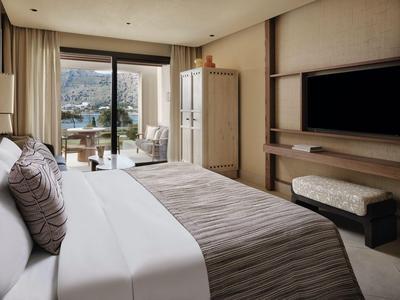 Chambre d'hôtel lumineuse avec lit double, télévision, coin salon et balcon avec vue panoramique.