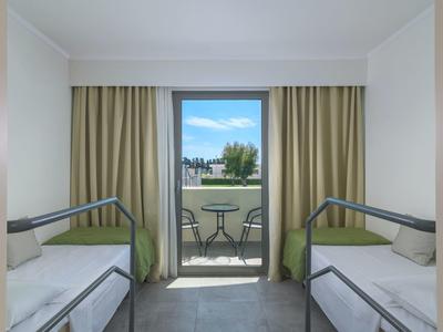 Habitación con dos camas individuales y balcón con vista al exterior en un hotel.