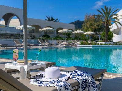 Strefa basenowa z leżakami, parasolami i napojami w słonecznym miejscu wypoczynkowym.