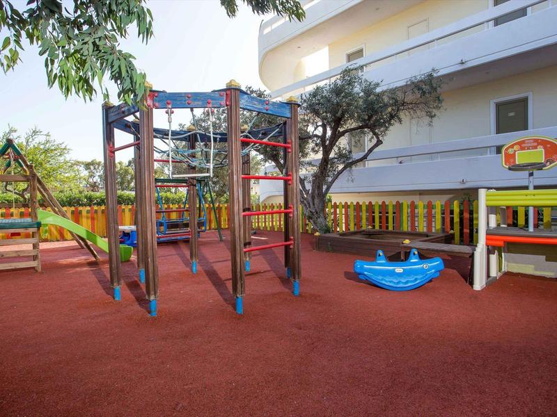 Área de juegos colorida y segura con columpios y estructuras de escalada en un hotel