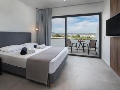 Nowoczesny pokój hotelowy z łóżkiem king-size i balkonem z widokiem na krajobraz.