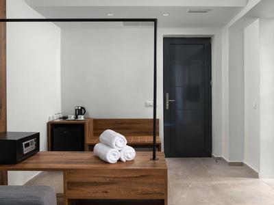 Nowoczesny obszar pokoju hotelowego z drewnianymi meblami, sejfem i białymi ręcznikami.