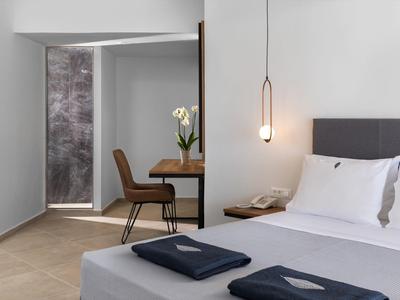 Nowoczesny pokój hotelowy z łóżkiem, biurkiem, krzesłem i wiszącą lampą.