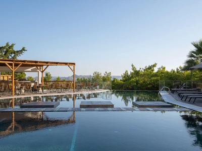 Basen z leżakami i pergolą pod czystym niebem, otoczony roślinami.