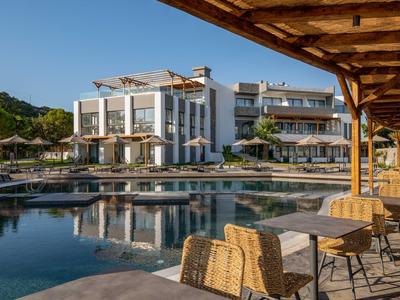 Nowoczesny kompleks hotelowy z basenem i meblami na tarasie pod niebieskim niebem.