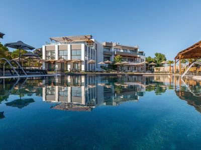 Nowoczesny kompleks hotelowy z dużymi przeszklonymi powierzchniami i basenem pod czystym niebieskim niebem.