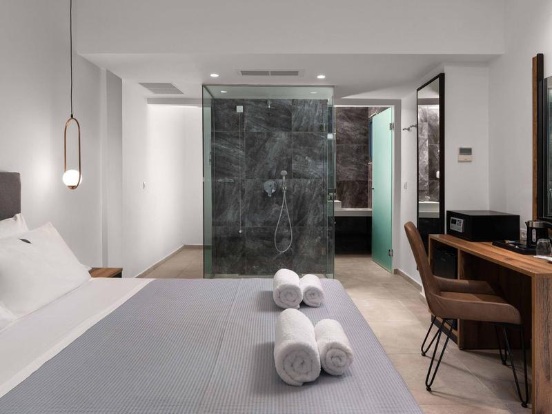 Nowoczesny pokój hotelowy z podwójnym łóżkiem, szklaną prysznicem i drewnianym biurkiem.