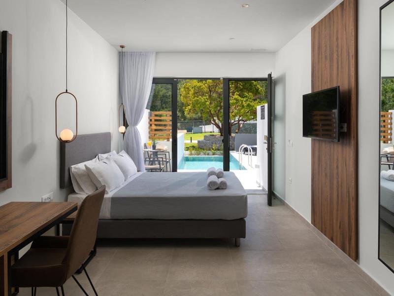 Nowoczesny pokój hotelowy z podwójnym łóżkiem, biurkiem, telewizorem i widokiem na basen.