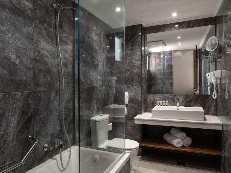 Nowoczesna łazienka z wanną, przeszkloną ścianą prysznica, toaletą i umywalką z ręcznikami.