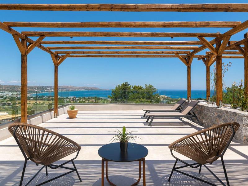 Taras z krzesłami i leżakami z widokiem na morze pod czystym niebem.