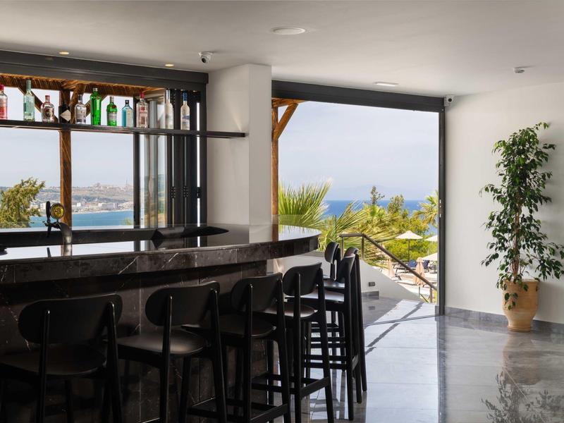 Nowoczesny bar z hokerami i widokiem na taras i morze.