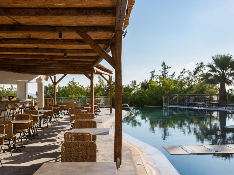 Zadaszony taras z miejscami do siedzenia obok basenu w hotelu w słoneczny dzień.