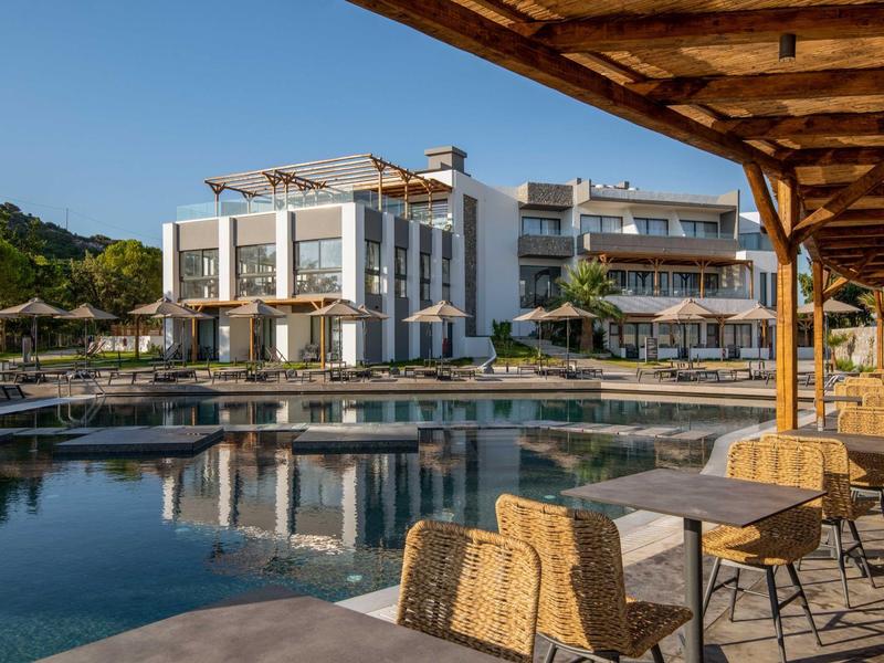 Nowoczesny kompleks hotelowy z basenem i miejscem do siedzenia pod drewnianą pergolą w słoneczny dzień