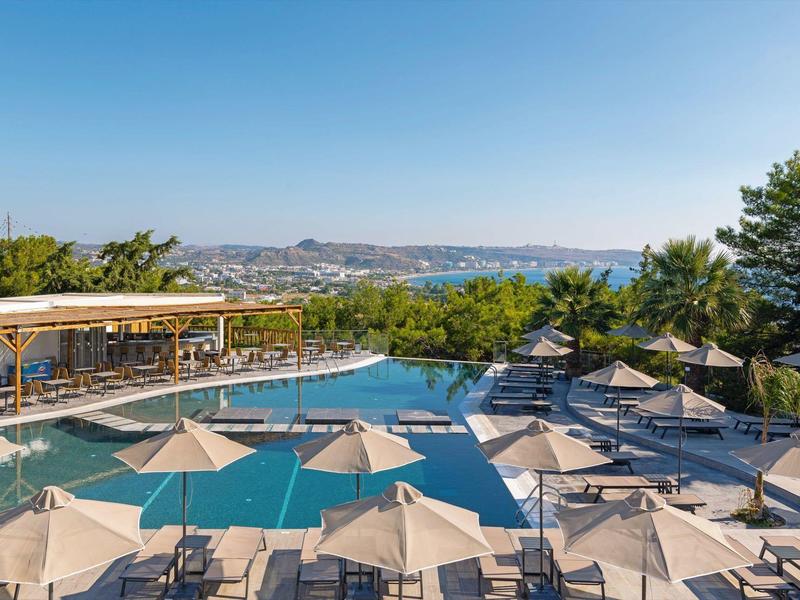 Basen na świeżym powietrzu z parasolami i miejscem do siedzenia, widok na miasto w tle.
