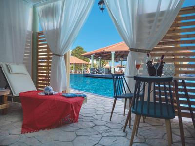 Gemütliche Lounge mit Liegestuhl, roter Decke, Tisch, Stühlen und Pool mit blauem Wasser.