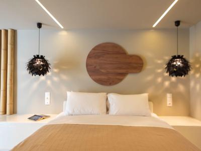 Modernes Schlafzimmer mit Doppelbett, hölzernen Wanddekorationen und stilvollen Hängelampen.
