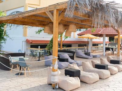 Parasols et chaises longues sous un pavillon en bois à côté d'un hôtel