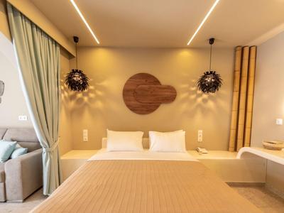 Modernes Schlafzimmer mit großem Bett, beige Bettdecke, runden Holzwanddekorationen und indirekter Beleuchtung.