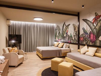 Modern eingerichtetes Hotelzimmer mit zwei Betten, Sessel, runden Teppichen und großer Blumenwand.