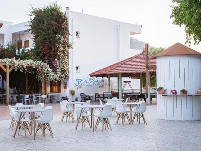 Espace extérieur d'un hôtel avec tables et chaises blanches sur sol pavé.