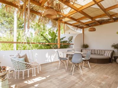 Terrasse couverte avec fauteuil suspendu, table à manger et canapés dans une ambiance détendue.