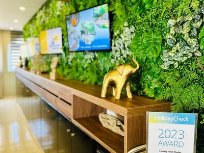 Moderner Empfang mit grüner Wand, Holzregal, goldenem Elefanten und Auszeichnung 2023.