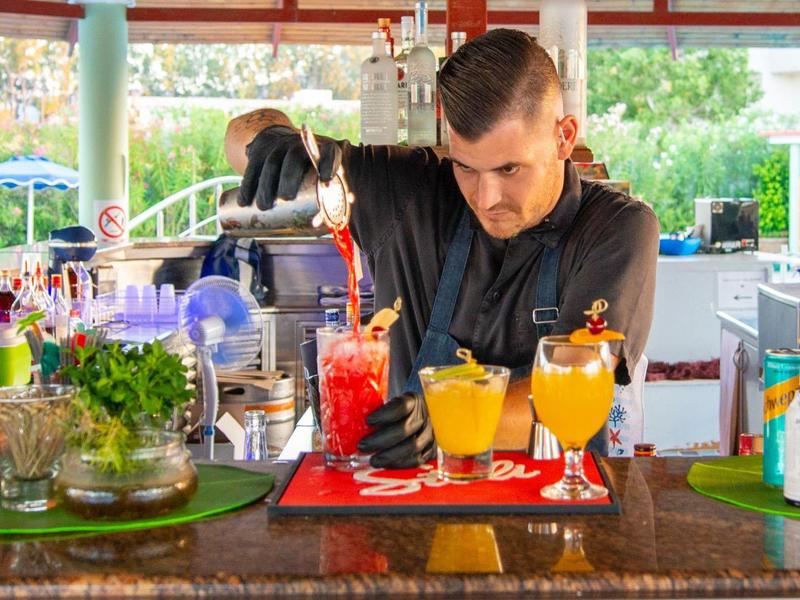 Barman prepara cocktail colorati al bar dell'hotel con ingredienti freschi.