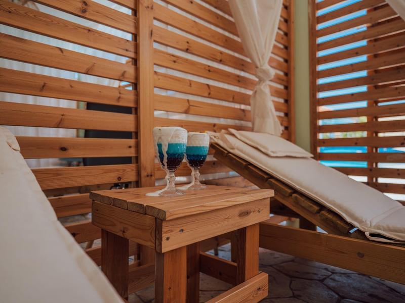 Due sdraio con un piccolo tavolo e due bevande all'interno di un padiglione di legno.