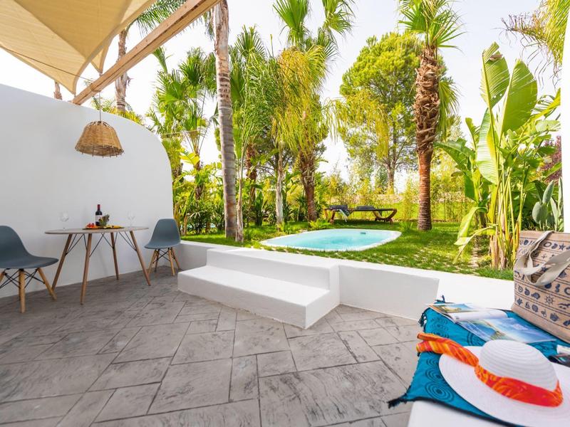 Terrazza con due sedie che si affaccia su una piscina e palme nel giardino