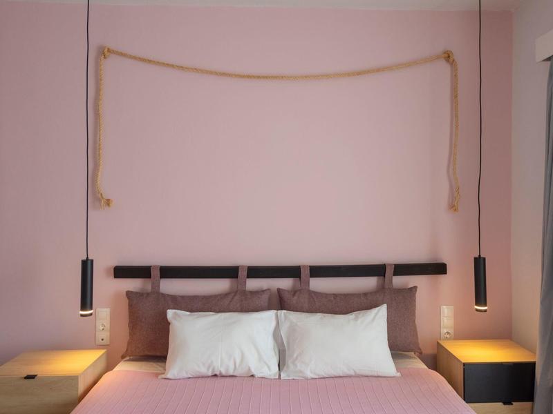 Camera da letto moderna con letto in legno semplice, pareti rosa e decorazioni minime.